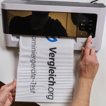 Eine Person betätigt einen Knopf eines Laminiergerätes.