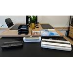 Drei Laminiergeräte von Fellowes, Leitz und Olympia stehen auf einem schwarzen Schreibtisch.