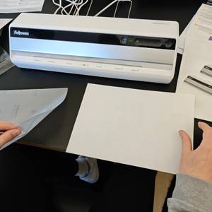 Ein Papier wird in eine Laminierfolie gelegt.