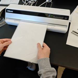 Ein Blatt wird durch das Laminiergerät Fellowes Saturn 3i geführt.