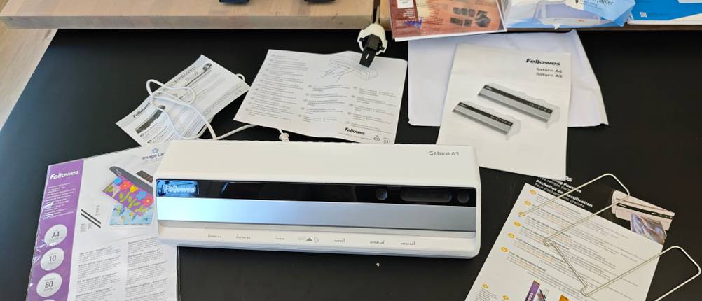 Das Zubehör des Fellowes Saturn 3i liegt auf einem schwarzen Tisch.