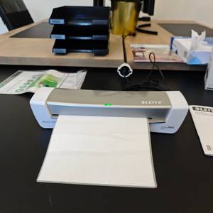 Ein Dokument gleitet durch das Laminiergerät Leitz iLAM 73680089.