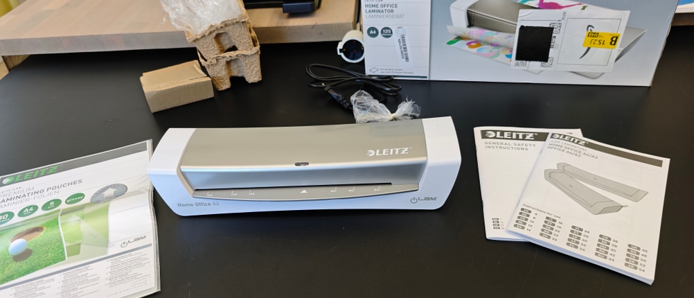 Das Zubehör des Leitz-Laminiergeräts liegt auf einem schwarzen Tisch.