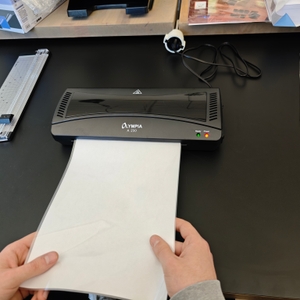 Ein Laminiergerät von Olympia zieht ein Blatt Papier ein.