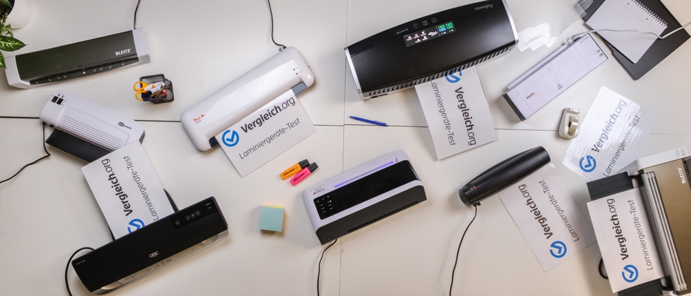 Verschiedene Laminiergeräte stehen auf einem Tisch und laminieren Papiere.