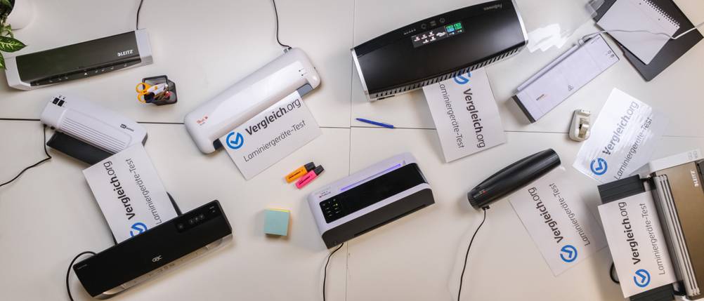 Verschiedene Laminiergeräte stehen auf einem Tisch und laminieren Papiere.