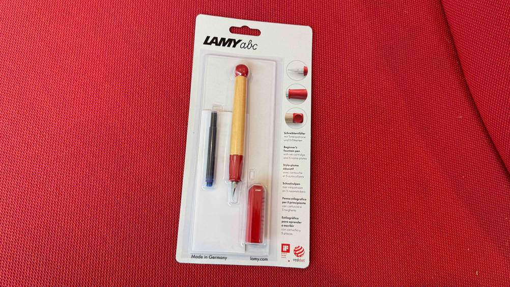 Auf einem roten Polster liegt ein getesteter Lamy-Füller in seiner transparenten Verpackung.