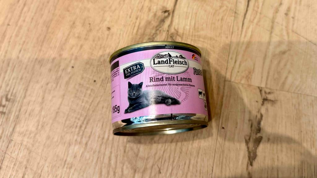 Eine Dose getestetes Landfleisch-Katzenfutter liegt auf einer Holzfläche.