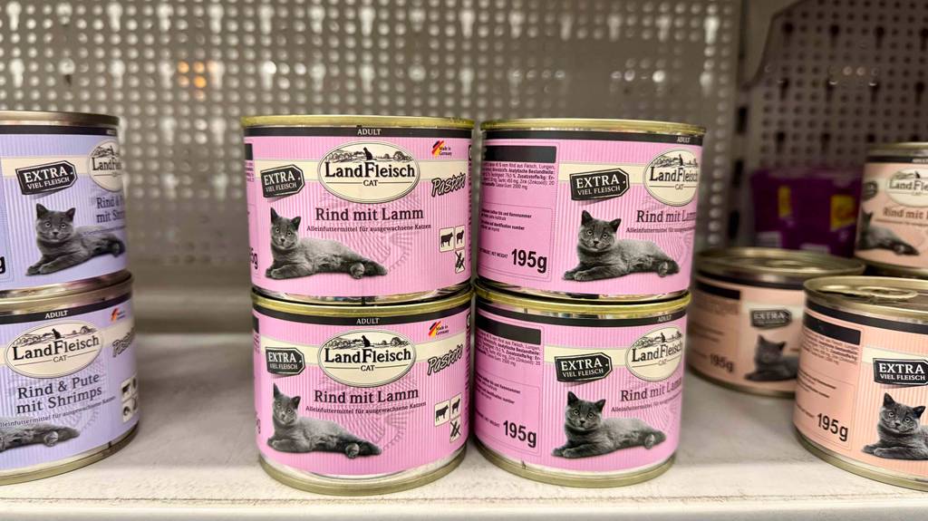 Landfleisch-Katzenfutter im Test: Mehrere Dosen unterschiedlicher Geschmacksrichtungen stehen gestapelt in einem Regal.