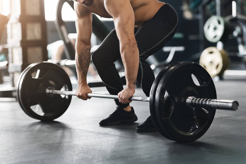 Langhantel-Test: Ein Mann trainiert mit einer Langhantel im Fitnessstudio.