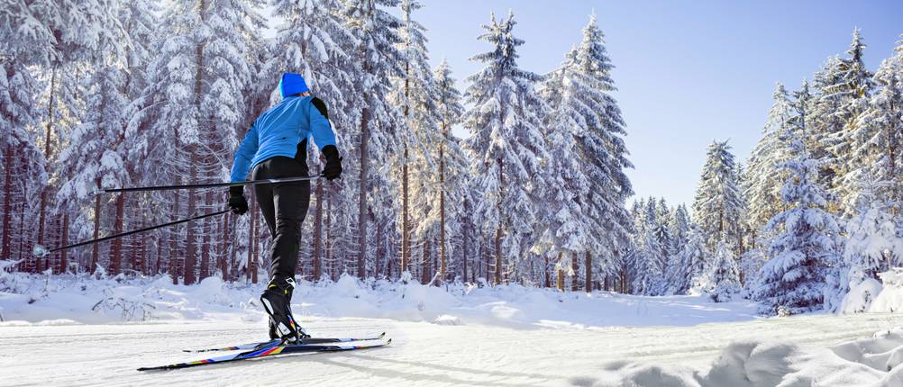 Langlaufhosen für Herren im Test: Skilangläufer, der vor einer imposanten Schneekulisse seinen Sport betreibt