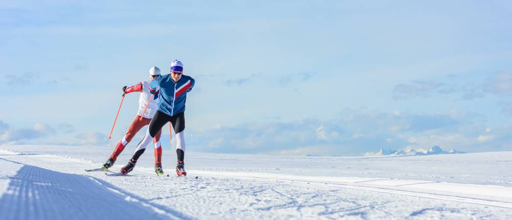 Langlaufhosen für Herren im Test: zwei Skilangläufer, die durch eine einsame Winterlandschaft fahren