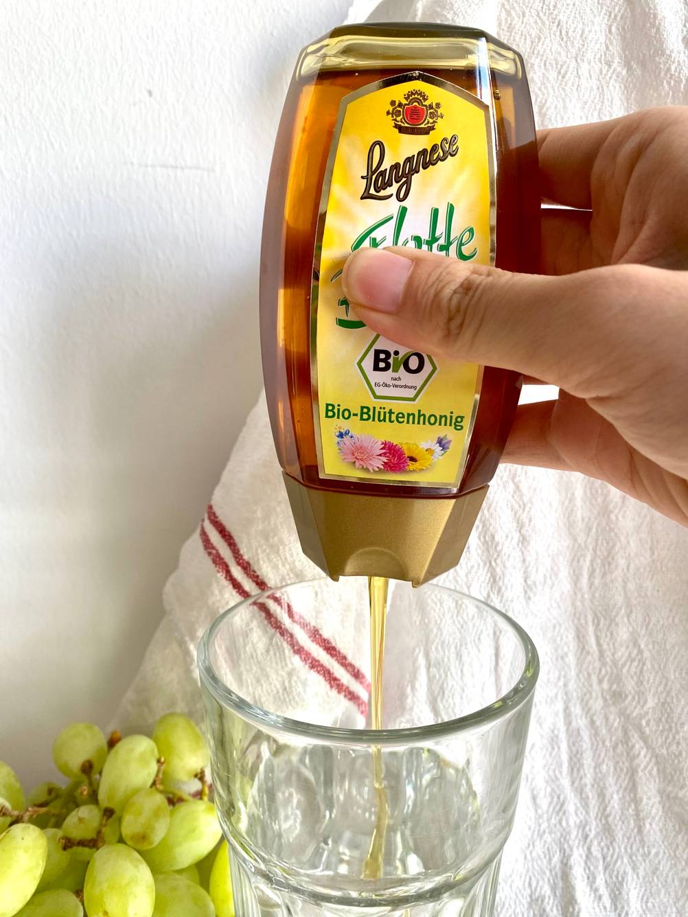 Bio-Blütenhonig wird in ein Glas gefüllt.