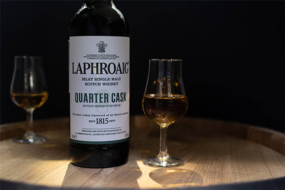 Der Laphroaig im Test: Eine Flasche Laphroaig Quater Cask auf einem Holzfass.