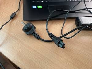 Ein Laptop mit Fokus auf das Ladekabel liegt auf einem Tisch.