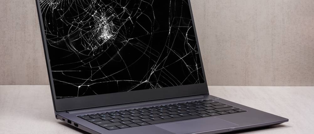 Laptop-Versicherung-Test: Bei einem grauen Laptop ist der Bildschirm defekt und zersplittert.
