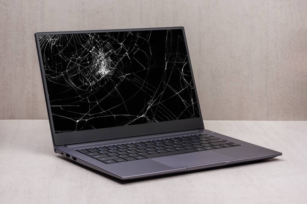 Bei einem grauen Laptop ist der Bildschirm defekt und zersplittert.