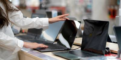 Eine Auswahl von Laptops in einem Laden und eine Kundin.