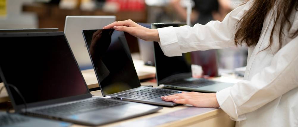 Eine Auswahl Laptops in einem Laden und eine Kundin.