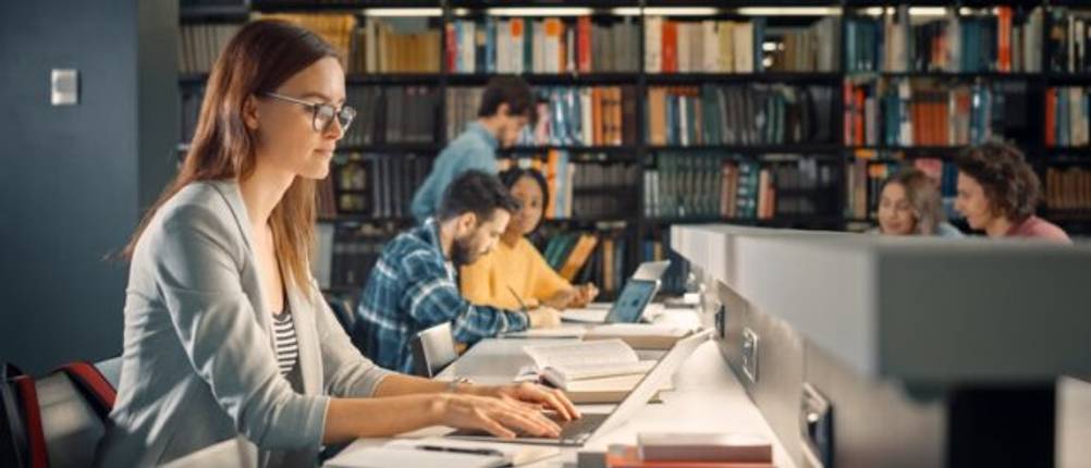 Eine Studentin in der Bibliothek am Laptop.