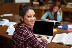 Eine Studentin mit Laptop in der Bibliothek.