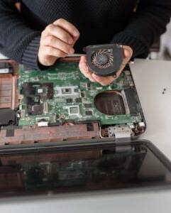 Ein Laptop ist aufgeschraubt und der Lüfter wird gereinigt.