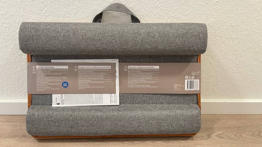 Die Rückseite des verpackten Laptopkissens vor einer hellen Wand.