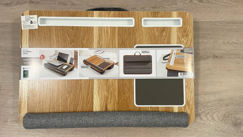 Das getestete Laptopkissen mit Verpackungsbanderole auf einem Holzboden.