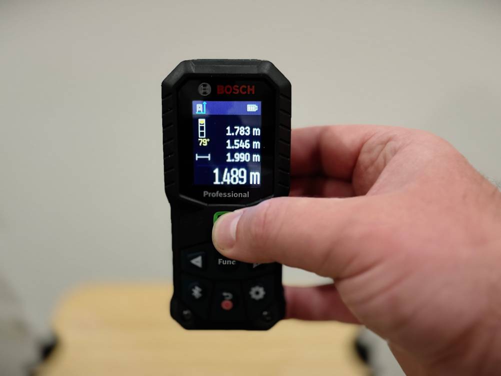 Eine Hand bedient den Laser-Entfernungsmesser von Bosch.