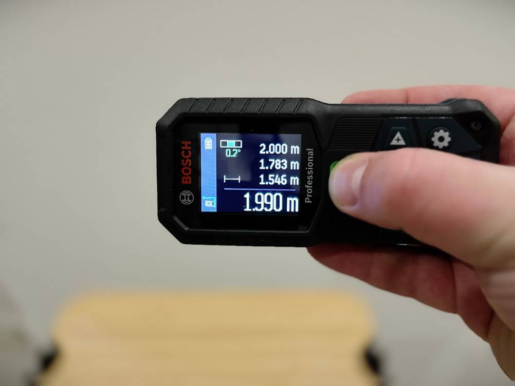 Eine Hand bedient den Laser-Entfernungsmesser von Bosch in waagerechter Position.