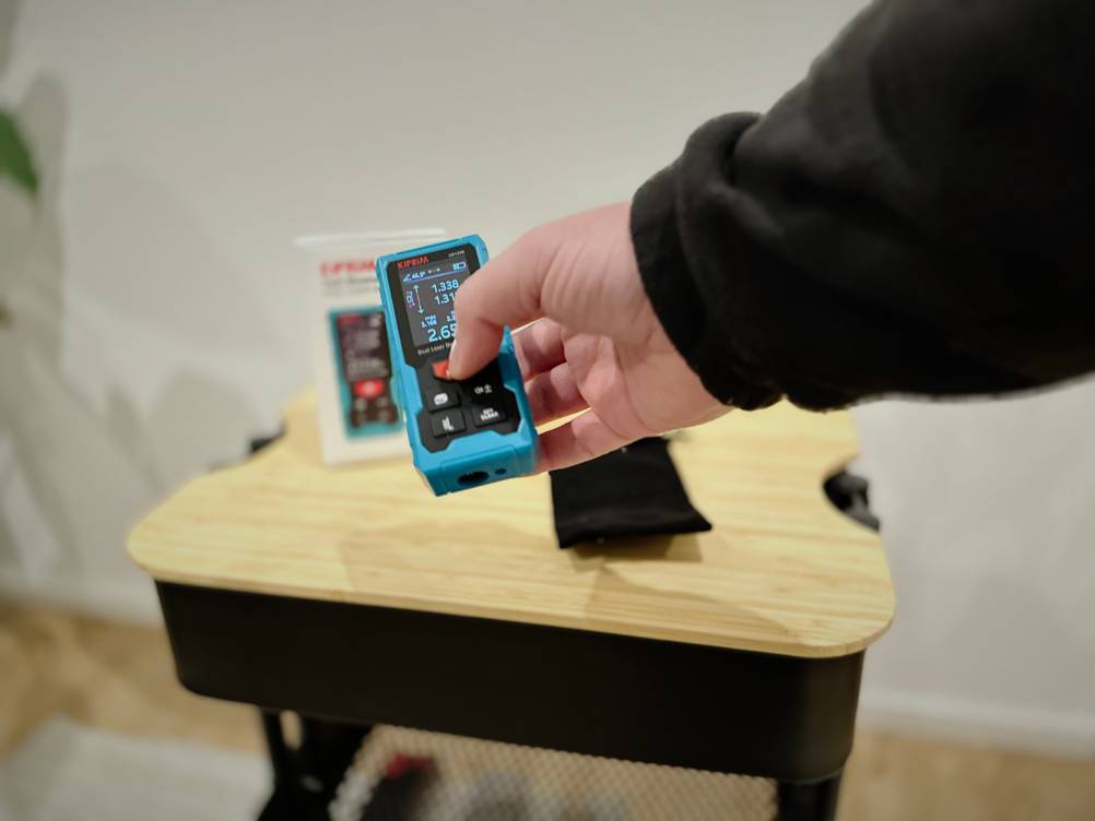 Eine Hand bedient den Laser-Entfernungsmesser von Kiprim.