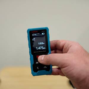 Eine Hand hält den Kiprim-Laser-Entfernungsmesser senkrecht.