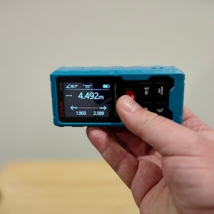 Eine Hand hält den Kiprim-Laser-Entfernungsmesser waagerecht.