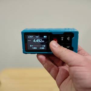 Eine Hand hält den Kiprim-Laser-Entfernungsmesser waagerecht.