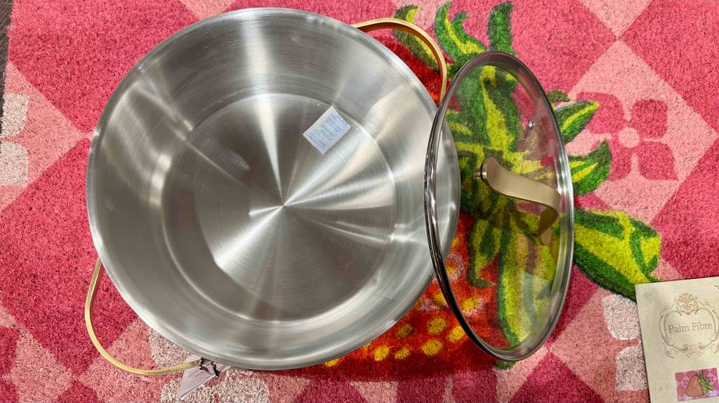 Ein Edelstahl-Kochtopf, 24 cm, im Test steht neben seinem Glasdeckel auf einem bunten Teppich.