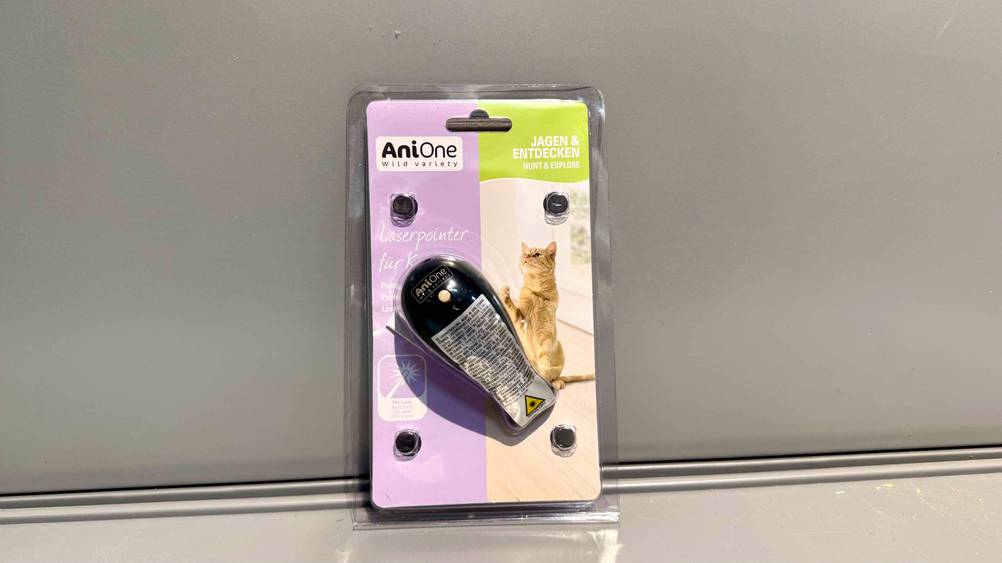 Vor einer grauen Wand lehnt der Laserpointer für Katzen im Test in seiner Verpackung.