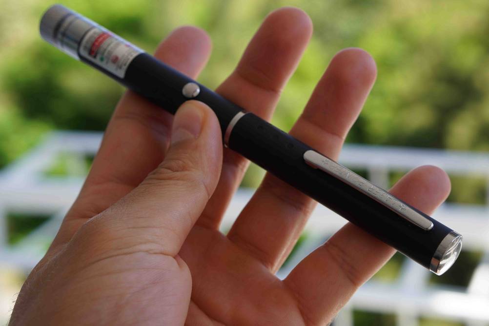 Detailansicht eines getesteten Laserpointers, der von einer Hand gehalten wird.