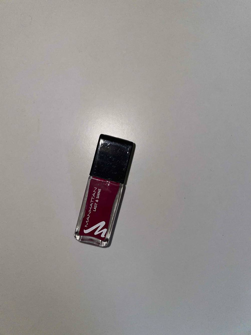 Ein dunkler Nagellack liegt zum testen auf einer weißen Fläche.
