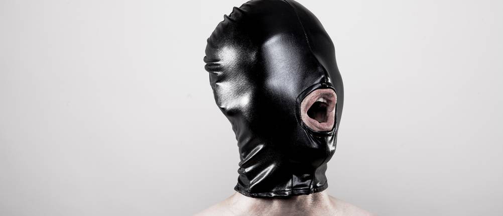 Latex-Maske im Test: Oberkörperfreier Mann trägt schwarze Maske aus Latex auf dem Kopf.