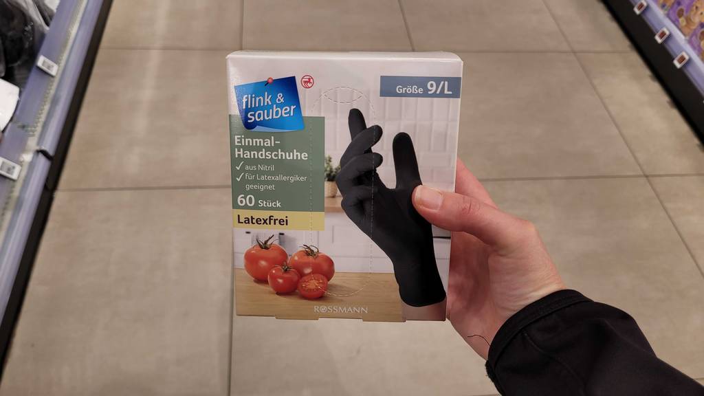 Eine Hand hält die getesteten Einmalhandschuhe-L in der Packung mit 60 Stück.