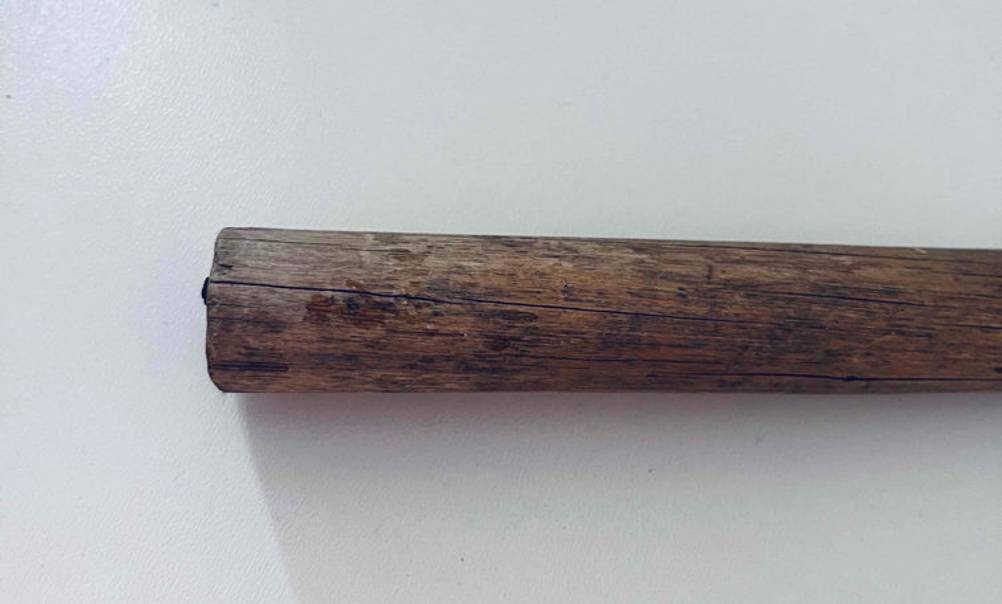 Detailansicht eines gebrauchten Holz-Griffs von einem Latthammer im Test vor weißem Hintergrund.