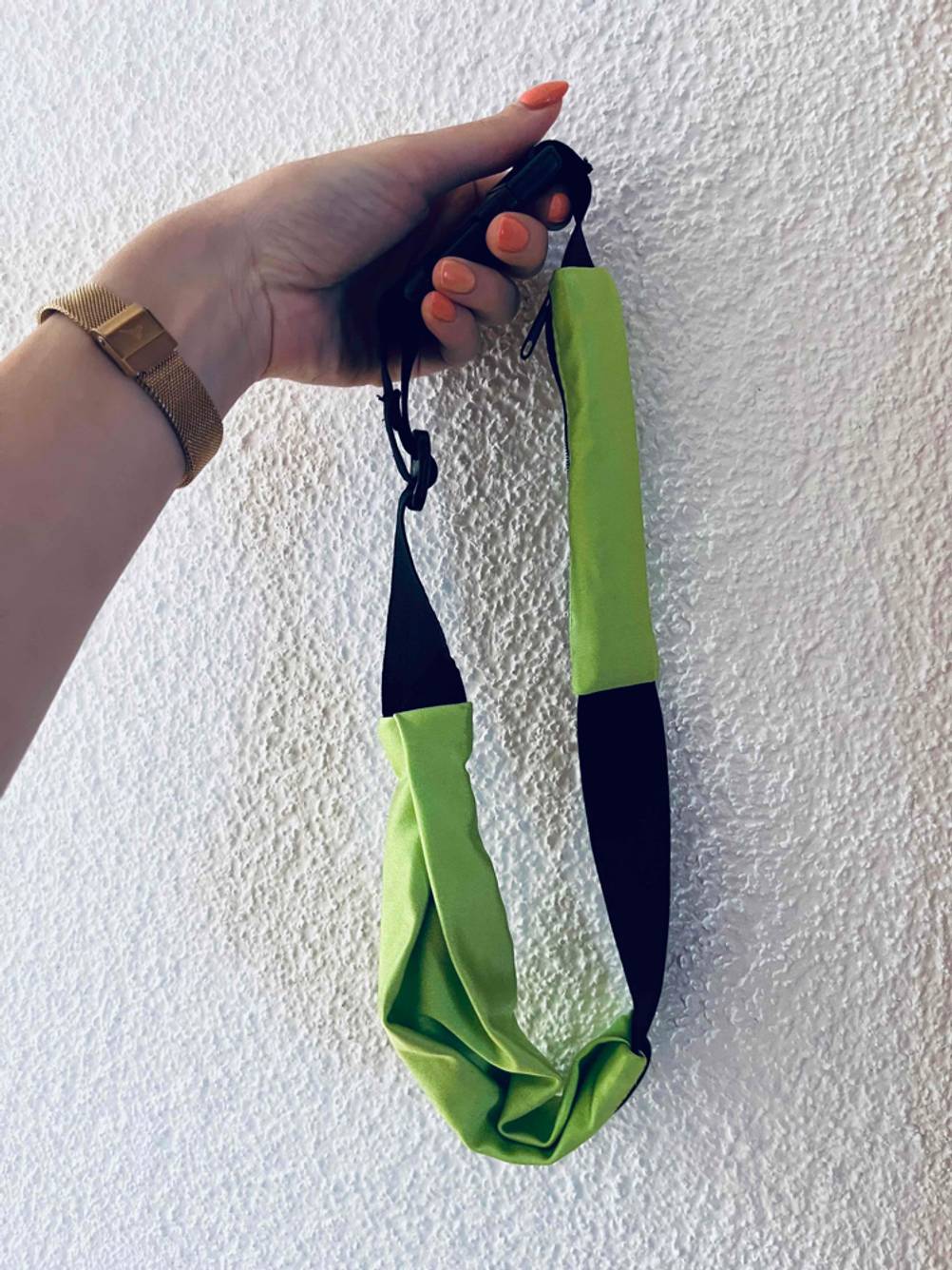 Getestet: Eine Hand hält einen geschlossenen Laufgürtel vor eine helle Wand.