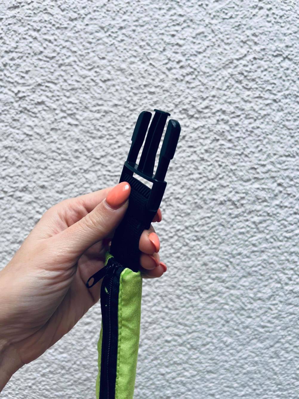 Laufgürtel getestet: Eine Hand hält eine Seite des Verschlusses vor eine helle Wand.