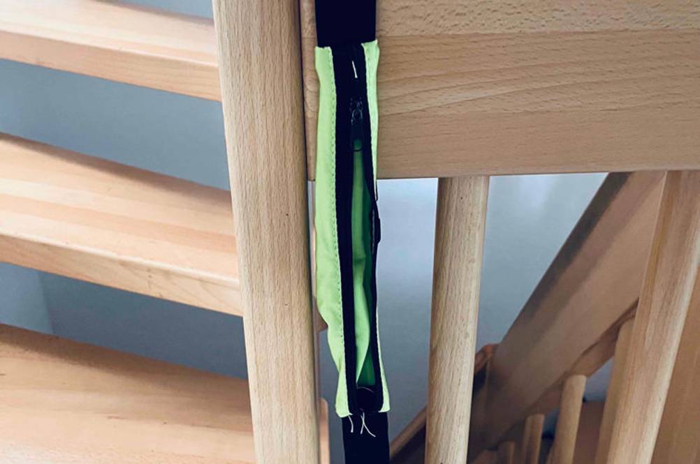 Ein getesteter Laufgürtel hängt über einem Holz-Treppengeländer.