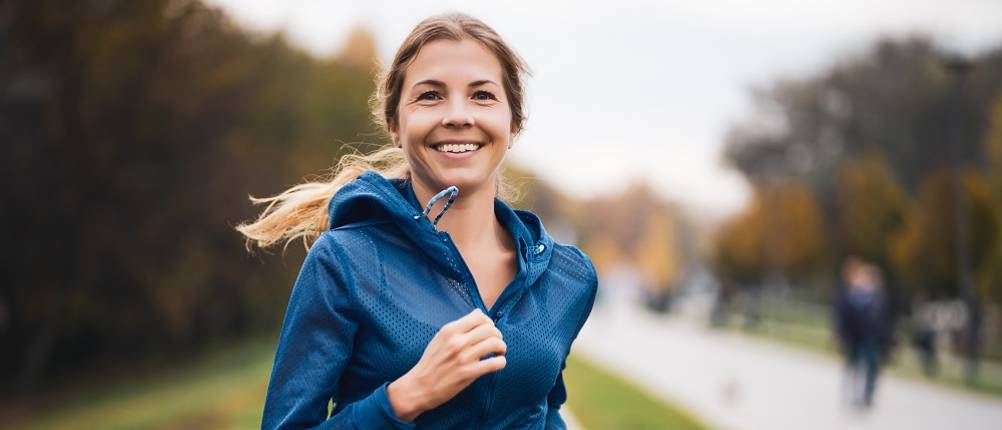 Damen-Laufjacke im Test: Eine Frau mit blauer Laufjacke beim Joggen.