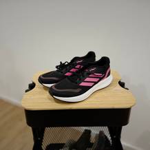 Die Adidas-Damen-Laufschuhe stehen ordentlich auf einem Rollwagen.