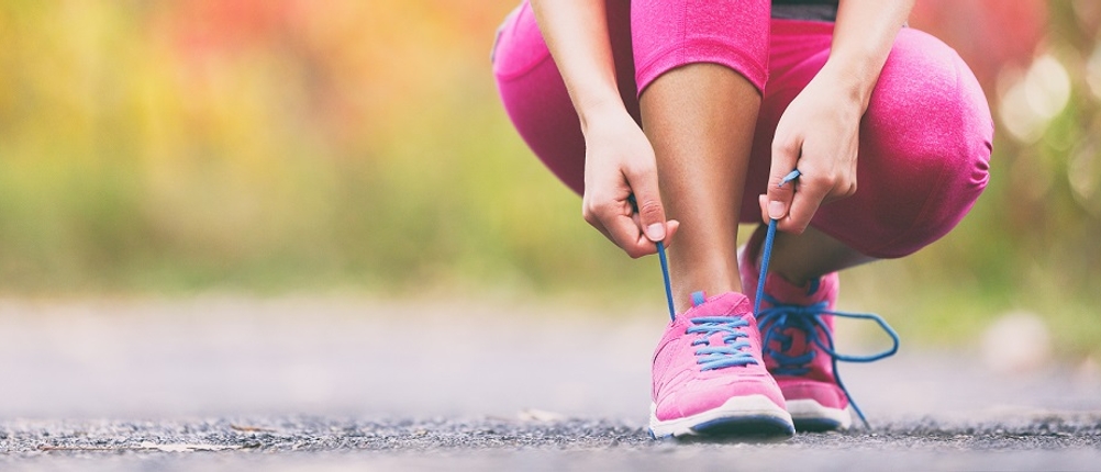 Laufschuhe-Damen-Test: eine Frau bindet sich gerade ihre pinken Laufschuhe zu
