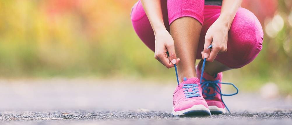 Laufschuhe-Damen-Test: eine Frau bindet sich gerade ihre pinken Laufschuhe zu
