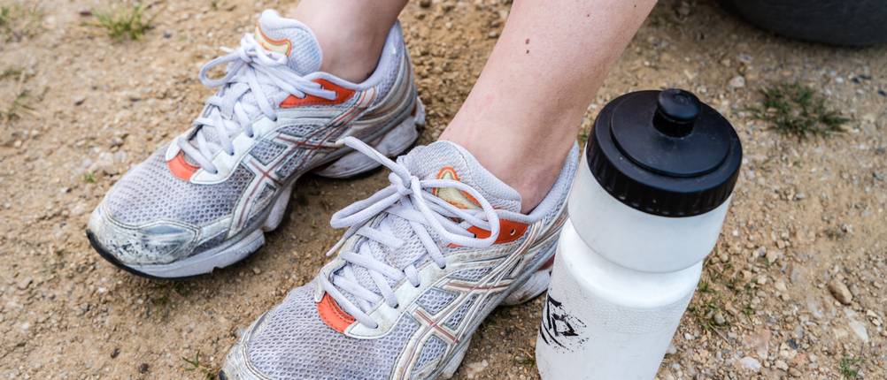 Laufschuhe für Damen im Test: Nahaufnahme von getragenen Laufschuhen während der Trinkpause auf unbefestigtem Untergrund