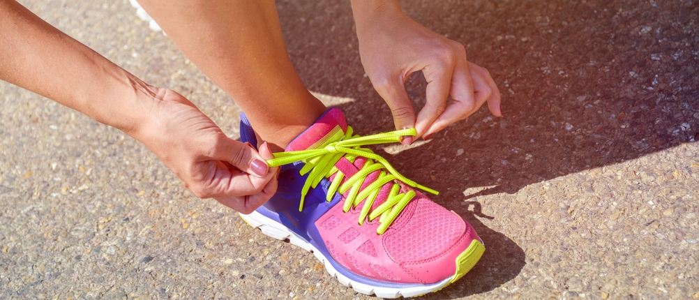 Laufschuhe für Damen im Test: Frau, die Ihre Schuhe schnürt